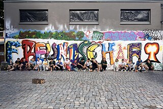 Ein Jugendlicher vor einer mit Graffiti besprühten Wand.