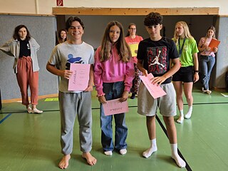 Jugendliche in einer Sporthalle empfangen Urkunden.