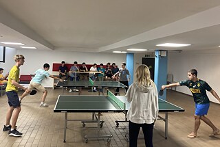 Jugendliche spielen Tischtennis in einem Kellerraum.