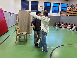 Zwei Jugendliche umarmen sich in einer Sporthalle.