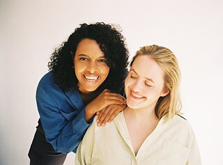 Zwei Frauen stehen nebeneinander. Sie lachen. 