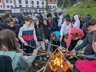Jugendlichen grillen Stockbrot über einem Feuer.