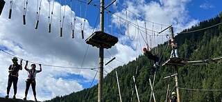 Jugendliche klettern in einem Hochseilgarten