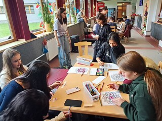 Jugendliche malen und basteln an Tischen.