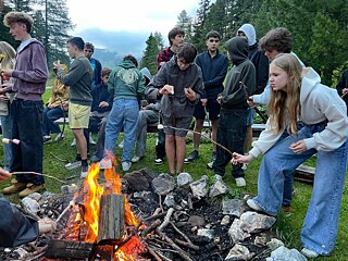 Jugendliche grillen Mashmellows an einem Lagerfeuer.