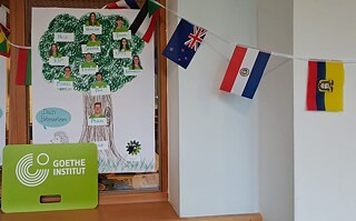 Ein Plakat mit Portraits und Namen, sowie Flaggen unterschiedlicher Länder