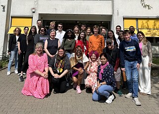 Group photo of the Summer Academy participants and leadership in front of the Lessing-Gymnasium with a teacher and the school director