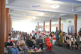 An audience in chairs. About fifty people
