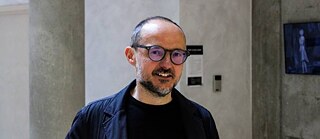 A smart looking man inside a modern building, looking into the camera