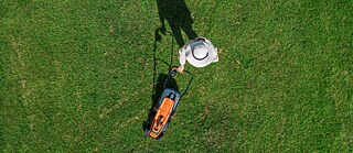 Bird's eye view: Woman mowing lawn