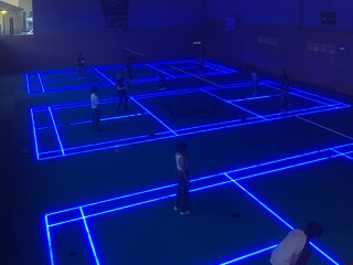 Hallentennis bei Neonlicht