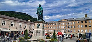 Repräsentativer rechteckiger Platz, in der Mitte das Mozartdenkmal, im Hintergrund die neue Residenz.
