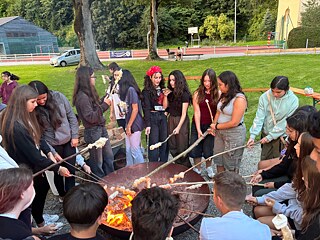 Jugendliche garen Stockbrot an einem großen Lagerfeuer.