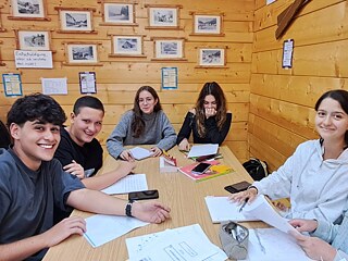 Jugendliche an einem Tisch lernen und lachen.