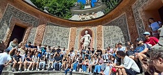 Große Gruppe Jugendlicher sitzt im Römisches Theater in den Wasserspielen von Hellbrunn.
