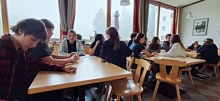 Jugendliche sitzen an Tischen.