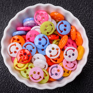 A medium-sized, white porcelain bowl stands on a black background. This is filled with colorful plastic smileys.