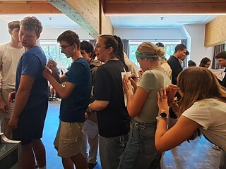 Junge Menschen stehen hintereinander und schreiben etwas auf die Rücken der anderen.