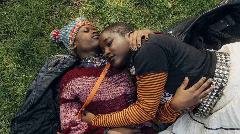 Lotta (Vanessa Yeboah, right) and Kojo (Thapelo Mashiane, left), lying entwined on the grass.