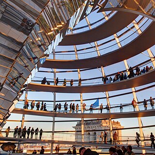 Personen gehen im Kuppeldach des Bundestags.