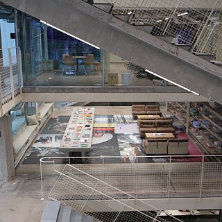 Et kig ind i kulturhuset Thoravej 29. Gennem glasvægge kan man se kontor- og opholdsrum på flere etager i bygningen, der er kendetegnet ved rå betonvægge og betonbjælker.