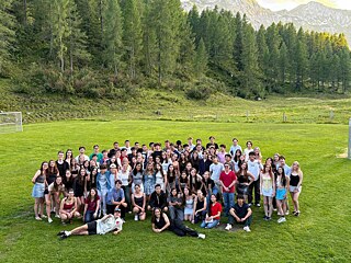 Große Gruppe junger Menschen auf einer Wiese in Obertauern