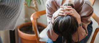 Eine Frau hält sich verzweifelt die Hände über den Kopf. 