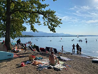 Menschen baden in einem See oder lieben am Seeufer und sonnen sich.