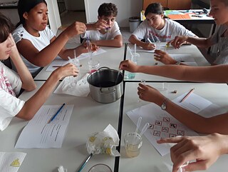 Jugendliche experimentieren an einem mit Plastik bedecktem Tisch.