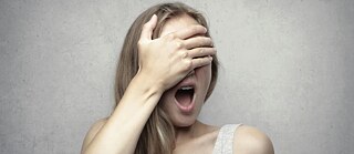 Ein Mädchen hält sich die Hand vors Gesicht.