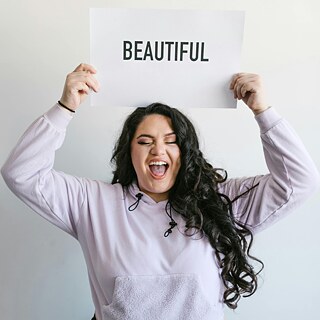 Eine Frau hält ein Schild hoch, auf dem "Beautiful" steht. 
