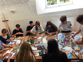 Jugendliche basteln an einem großen Tisch.