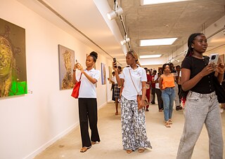 Kunstvoller Moment bei Kouman 2025 in Abidjan, wo die Teilnehmer die Ausstellungsstücke fotografieren und betrachten.