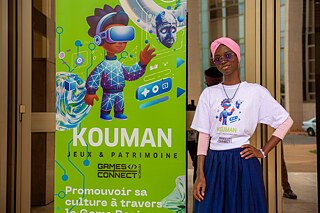 A Kouman workshop participant in front of a Kouman banner. 