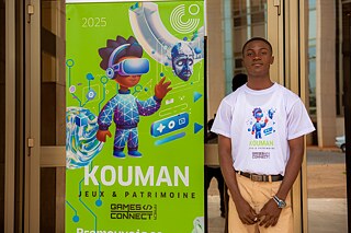 A Kouman workshop participant in front of a Kouman banner. 
