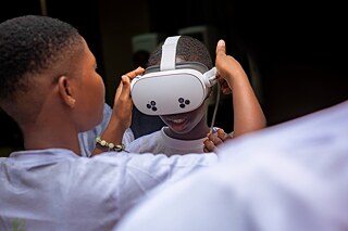 A Kouman workshop participant helping another participant to put on VR glasses. 