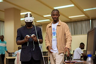 A Kouman workshop instructor standing next to a participant wearing and using VR glasses. 