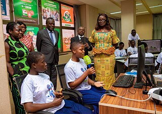 A group of Kouman workshop participants gathering with individuals dressed in colorful traditional attire, engaged in conversation. 