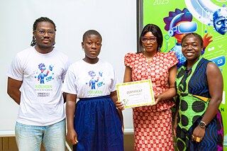 Group photo from a Kouman event in 2025, showcasing four participants standing together. One individual holds a certificate of participation, with a vibrant digital-themed banner in the background highlighting the year 2025.