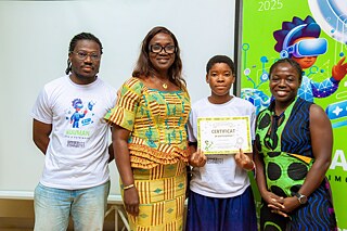 Group photo from a Kouman event in 2025, showcasing four participants standing together. One individual holds a certificate of participation, with a vibrant digital-themed banner in the background highlighting the year 2025.