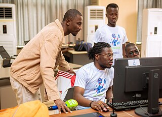 A group of Kouman workshop participants working together on a computer.
