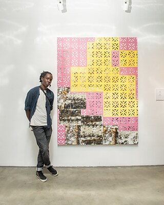 Der vom Goethe-Institut Jordanien zur Teilnahme an der Ausstellung “Arts & Dialogue” eingeladenen Künstler Nicholas Mboya vor seiner für die Ausstellung angefertigten Arbeit.