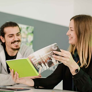 Frau zeigt Mann die Broschüre "Mein Deutschlandheft"