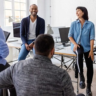 Eine Gruppe von Lehrer*innen unterhält sich. Die Menschen sind entspannt und lachen.