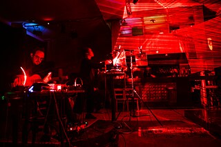 A male person plays the guitar in a music studio.