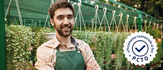 Ein junger Gärtner mit hängenden Blumentöpfen im Hintergrund