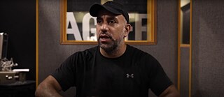 Hajar Zahawy wird in einem Raum mit schallisolierten Wänden interviewt. Er ist schwarz gekleidet (schwarzes T-Shirt und schwarze Kappe).