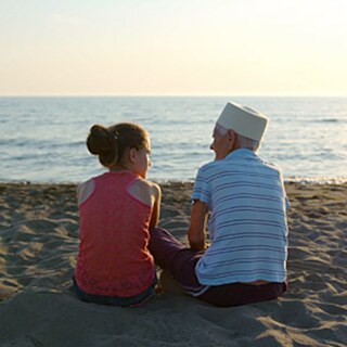 Zwei Personen sitzen am Strand