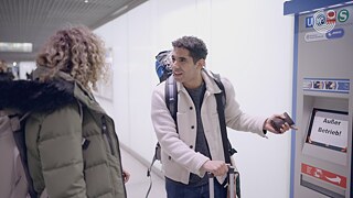 Zwei Personen stehen vor einem defekten Fahrkartenautomaten mit dem Hinweis „Außer Betrieb!“.