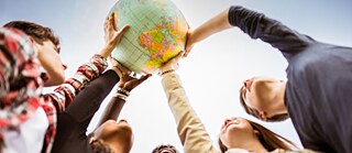 Jugendliche halten Weltkugel in die Luft.